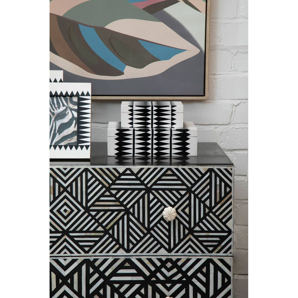 Patterned dresser with abstract art on a white brick wall