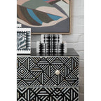 Patterned dresser with abstract art on a white brick wall